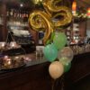 luxe helium boekt met 2 geelgouwen cijfer van ieder 66 cm met daaronder 5 helium ballonnen in 3 kleuren groen 1 doorzichtig met een confetti printje en 1x blush